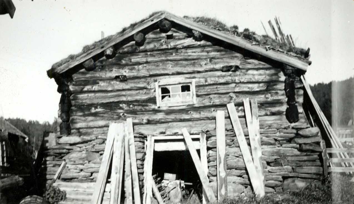 Engan, Os, Nord Østerdal, Hedmark 1941. Kortveggen til fjøs i stein og tømmer med torv på taket. Plank lent mot veggen. Nå på Norsk Folkemuseum.