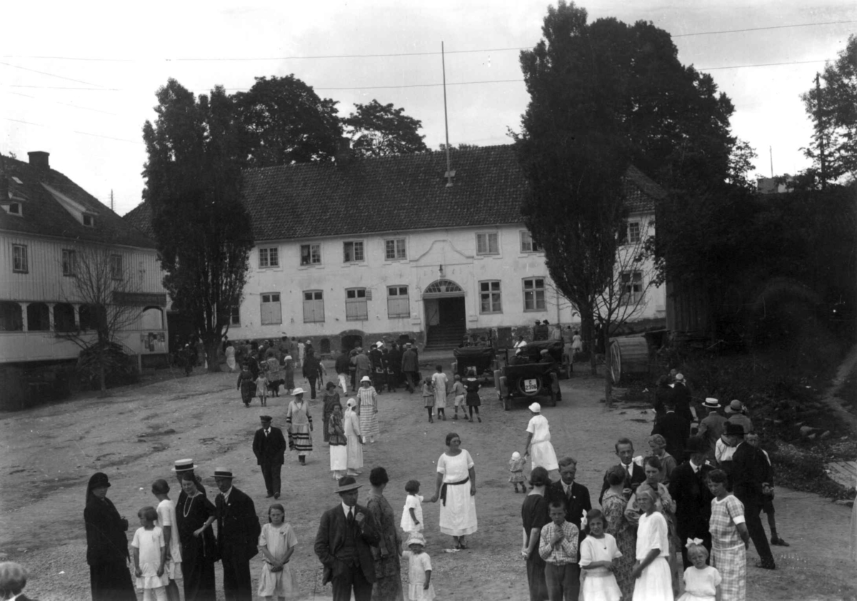 Son, Vestby, Akershus 1924. Festkledde mennesker foran hvite bygninger. Spinnerigården i bakgrunnen.
Brant 17. mai 1976. Biler. Trær.