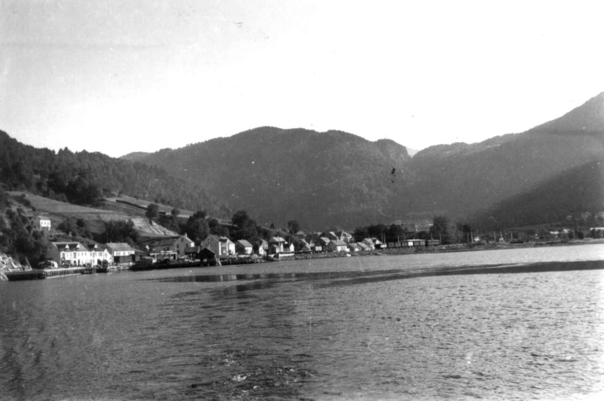 Voss 1939. Vangsvatnet med bebyggelse. Landskap med jorder. Høyonn. Skog og fjell i bakgrunnen.