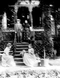 Familiegruppe i trapp foran verandaparti. Sigrid f. Holm (mu