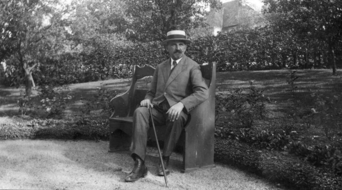 Direktør Hans Aall sittende på en benk i hagen i 1929.