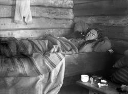 Bernt Jebsen ligger i senga i en av husene på Trøan. Fotogra