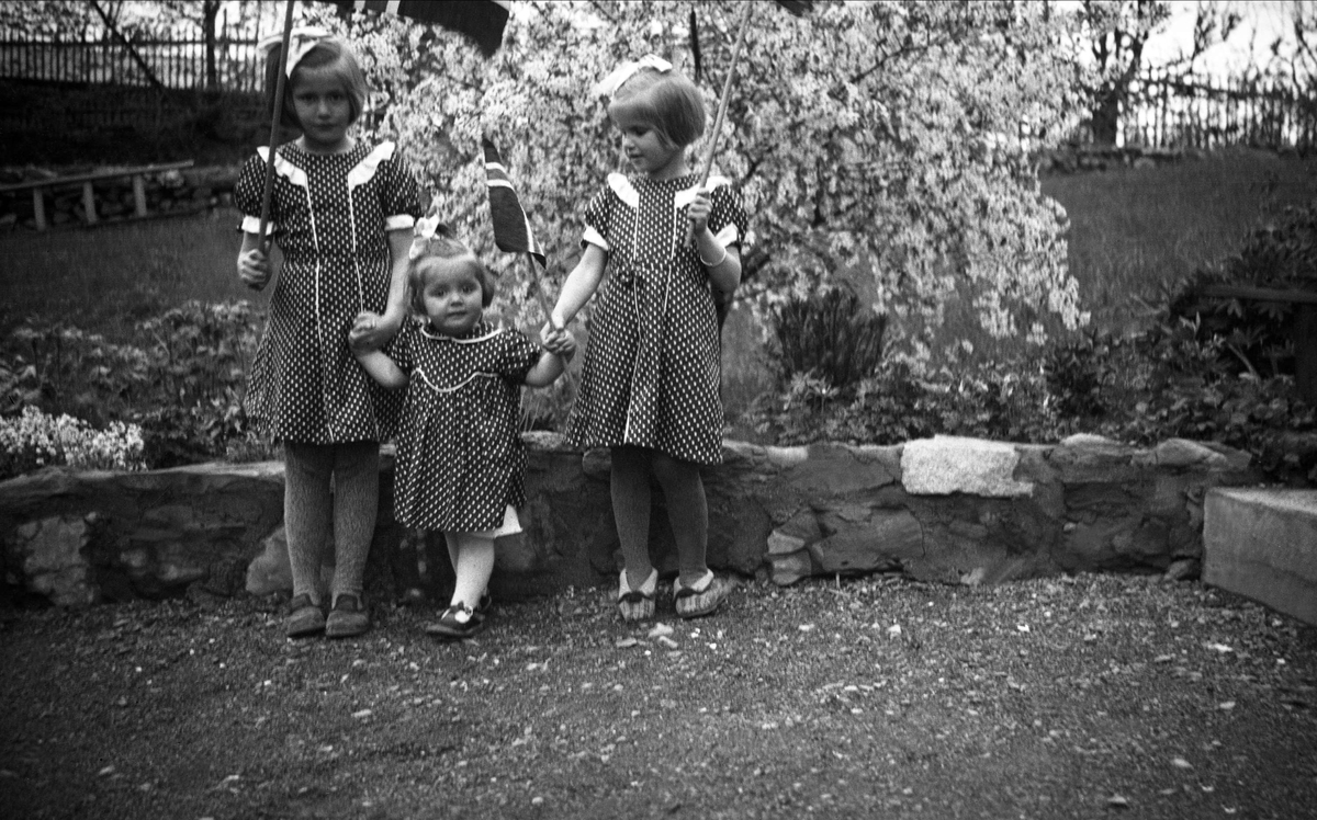 Siri, Kari og Guri Arentz kledd med kjoler og norske flagg i hagen på P.T. Mallings vei 4 på Bygdøy. Fotografet 1936.