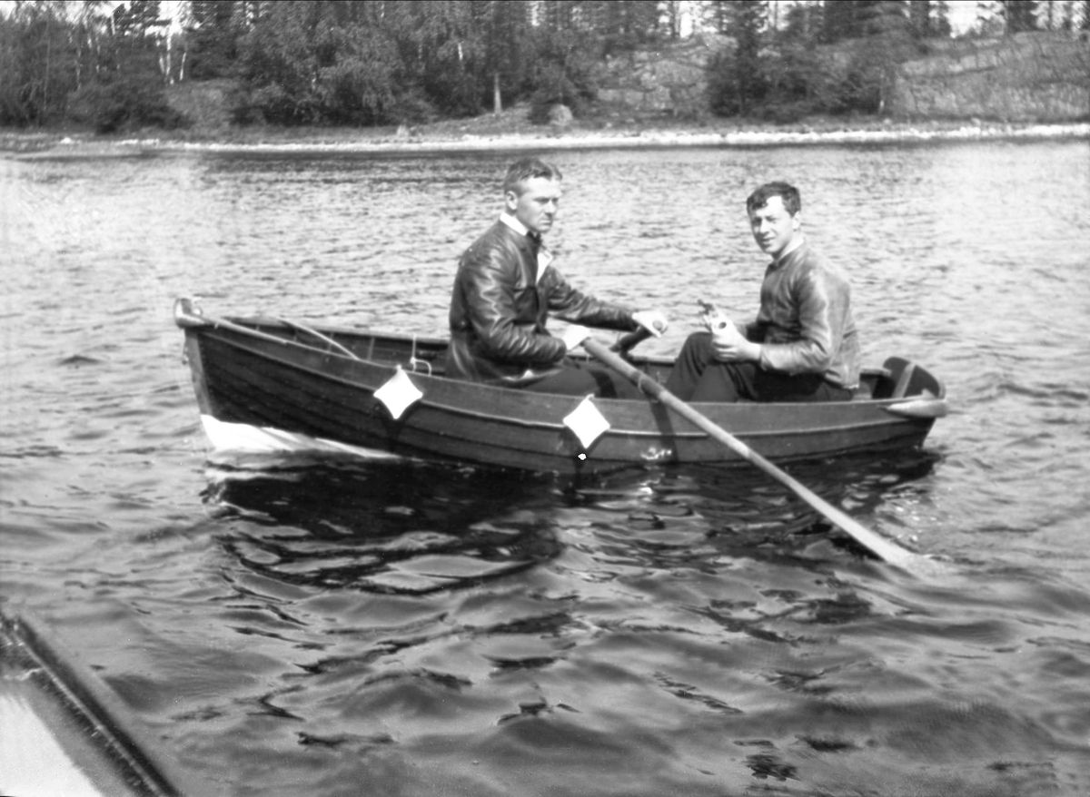 To menn ror i en robåt. Robsahm og Lund.