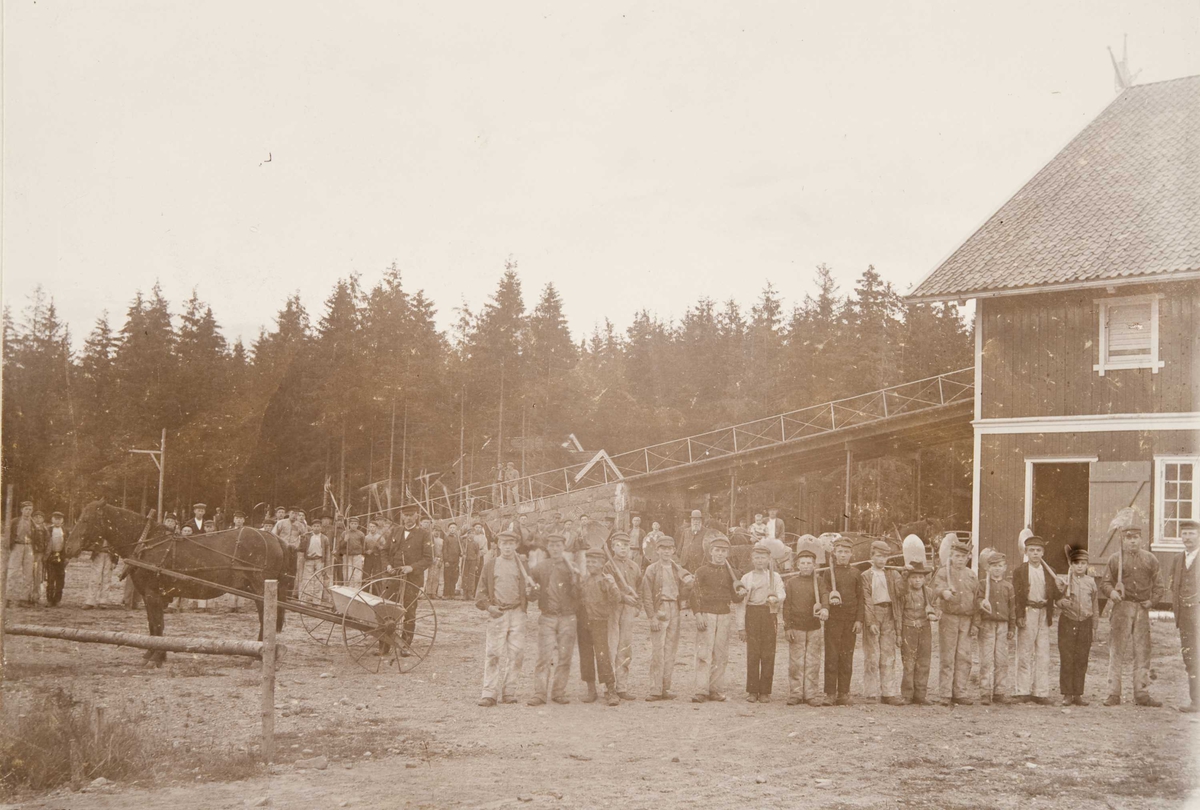 Låvebygningen på Bastøy skolehjem, Bastøya, ca. 1903. Elevene står oppstilt utenfor med gårdsredskaper.