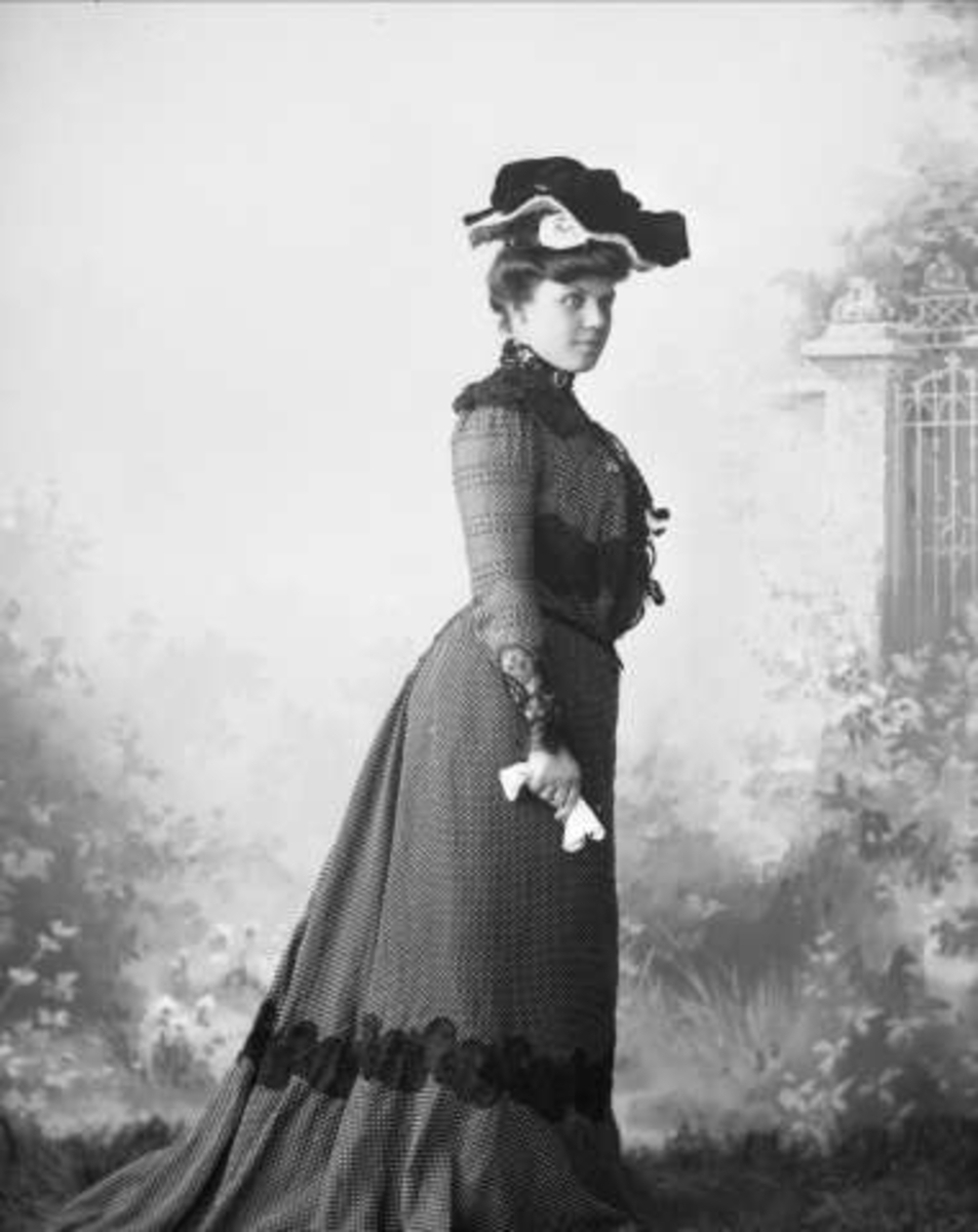 Portrett, kvinne i mørk kjole, med hatt. Mrs A. S. Olney.