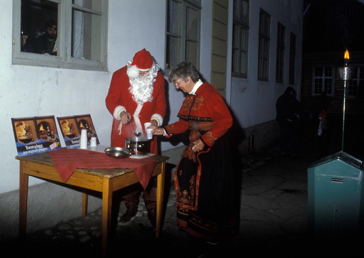 Julemarked på Norsk Folkemuseum i 1987. Julenissen serverer gløgg i museets gamleby til Randi Graff, som er kledd i telemarksbunad.