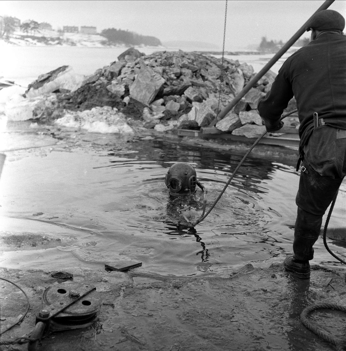 Trelleborg Gummi legger ut slange ved Sarpsborg, mars, 1959. Dykker i vannet.
