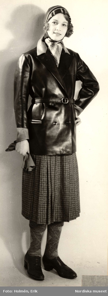 Nordiska Kompaniet, dammode. Kvinna i svart skinnjacka, veckad smårutig kjol, knästrumpor  och grova skor