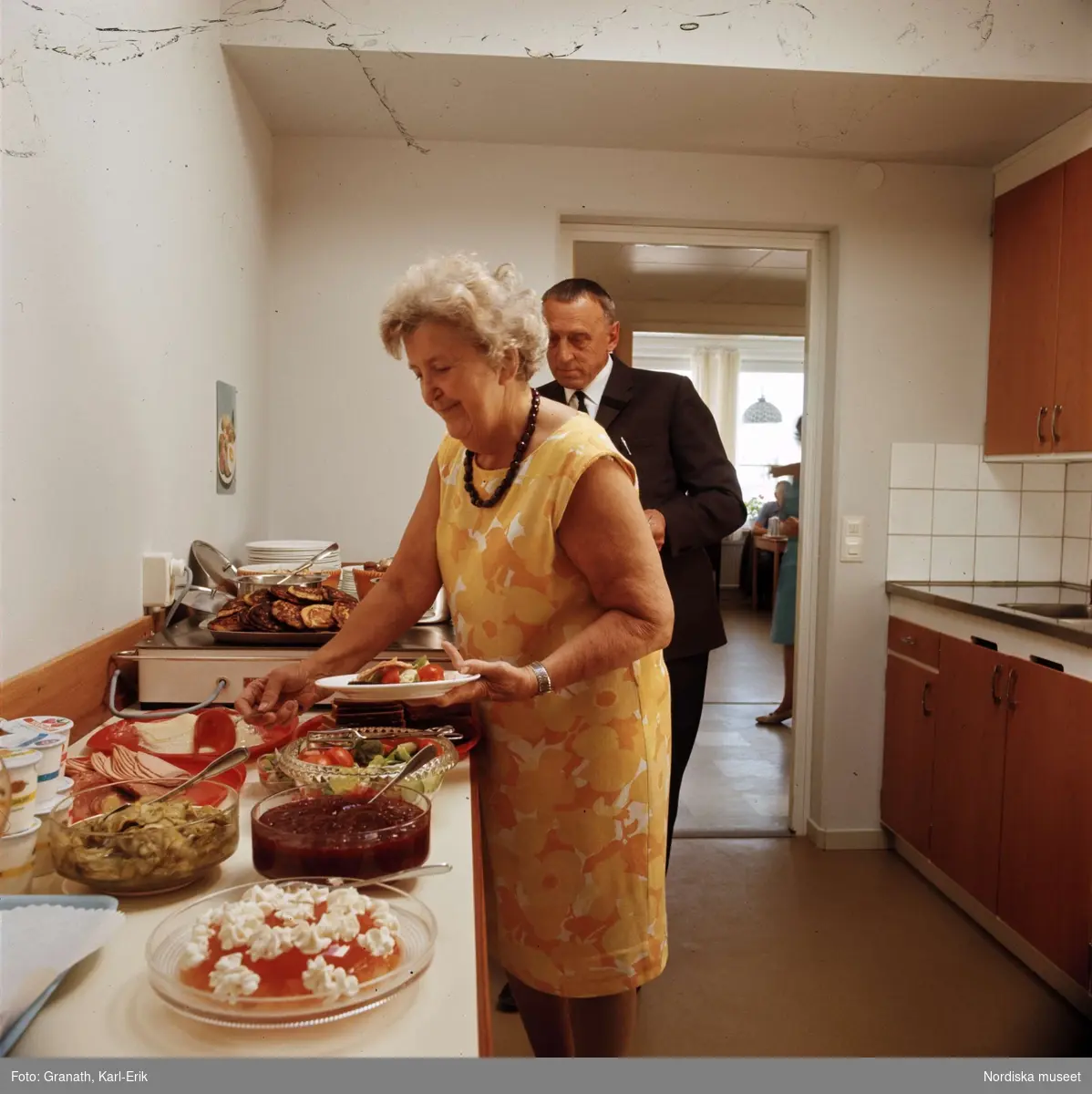 "Restaurang vid servicecenter i Jakobsberg, Stockholm". Äldre man och kvinna hämtar mat från ett uppdukad buffébord