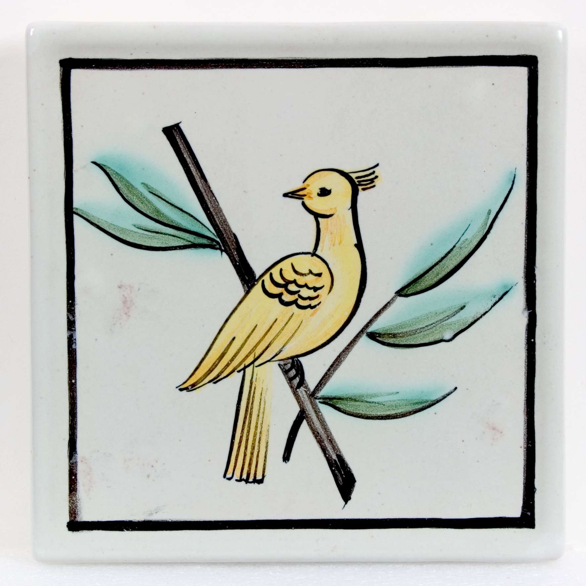 Vitglaserad med målad dekor i gult, svart och grönt föreställande en fågel på en kvist. Stämplad: S:T ERIK UPSALA. Målat i brunt : P 110.

