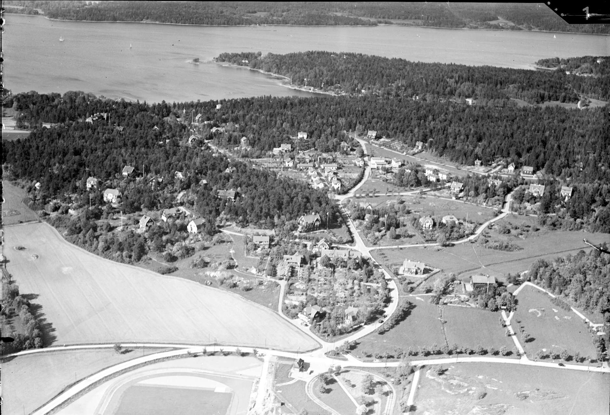 Flygfoto över mindre samhälle nära större sjö, okänd ort, år 1936