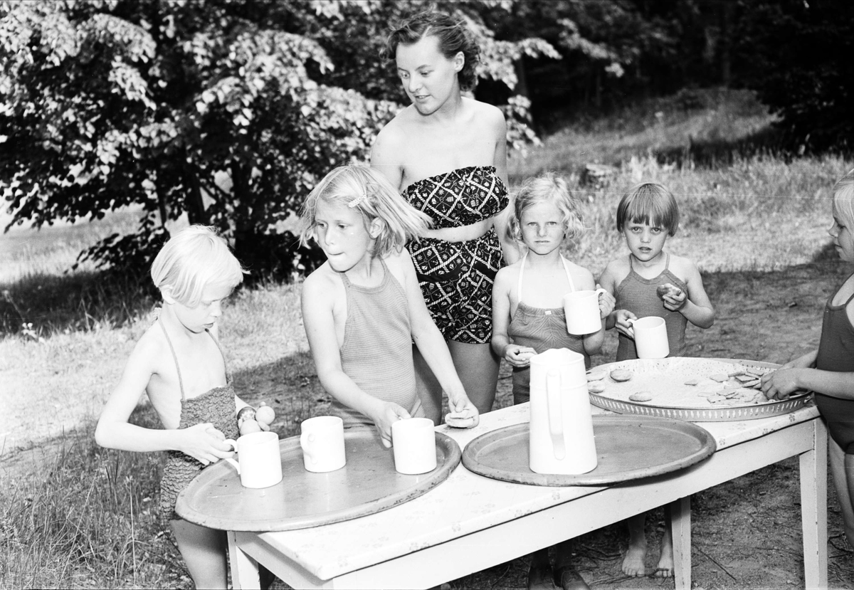 "Upsalasmåttingar på grönbete" - "folkskollärarinnan Barbro Carlsson övervakar kolonibarnens mellanmål", Eda skollovskoloni, Lagga socken, Uppland juni 1954