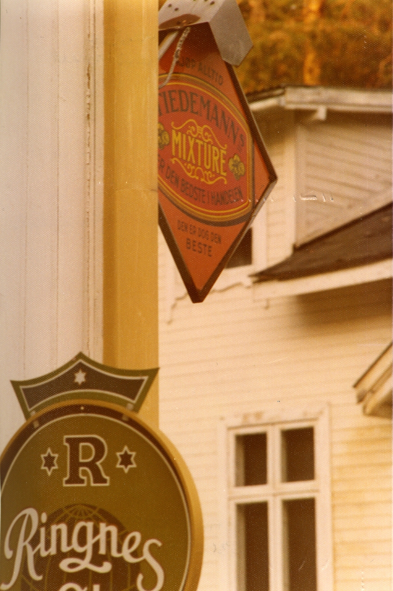 Reklameskilt på fasaden til forretningen N. G. Rudi.