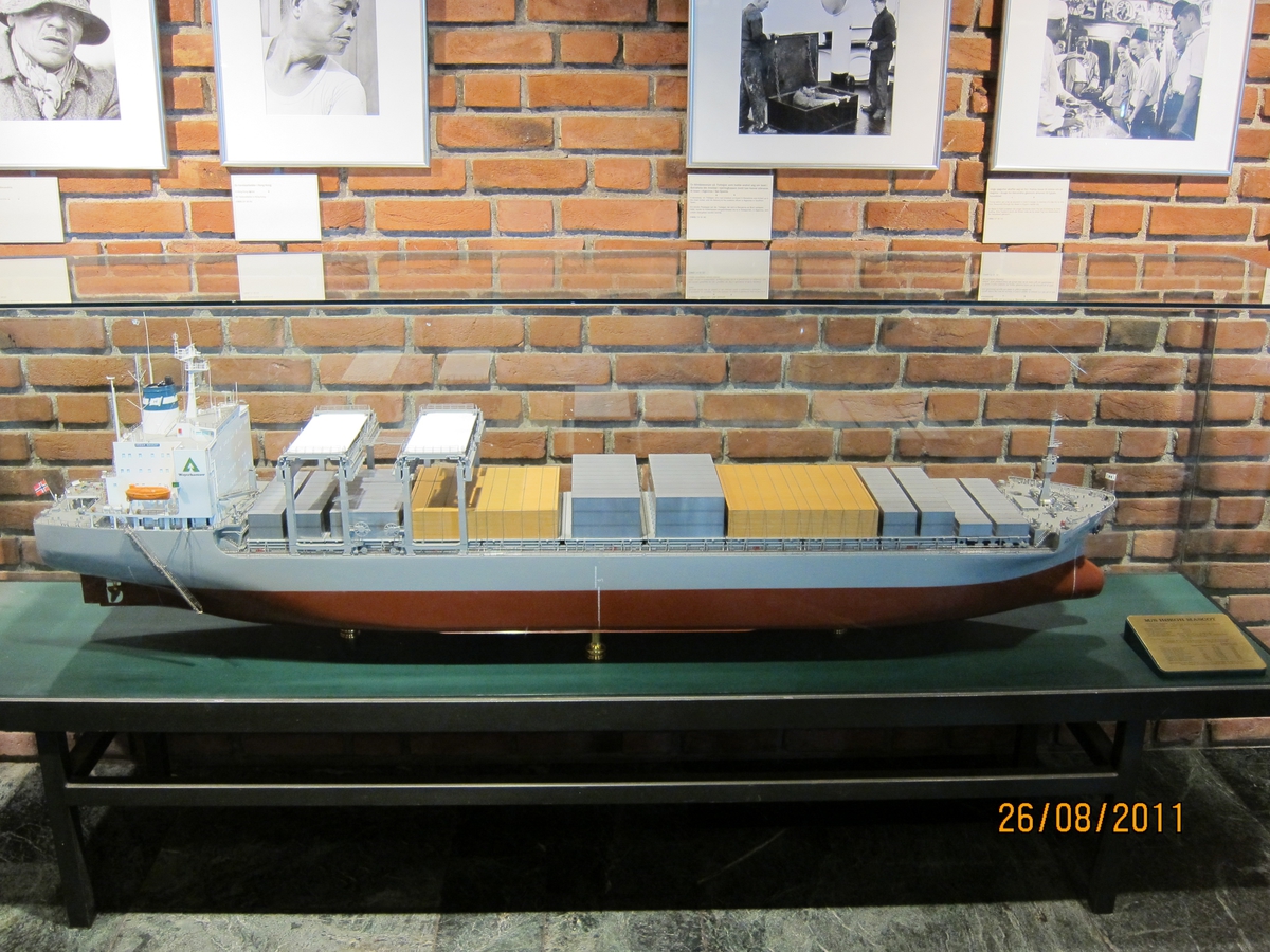 Skala  1:100 . Hvitt overbygg med firmalogo Weyerhaeuser på sidene, blå skorstein med hvitt flagg med blå H, grått fribord, brunrødt undervannsskrog. Open hatch-skip som også tar  containere og tømmer .