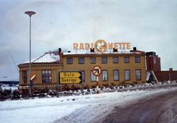 Radionette, lysreklame på hus med veiskilt foran, kanskje Sa