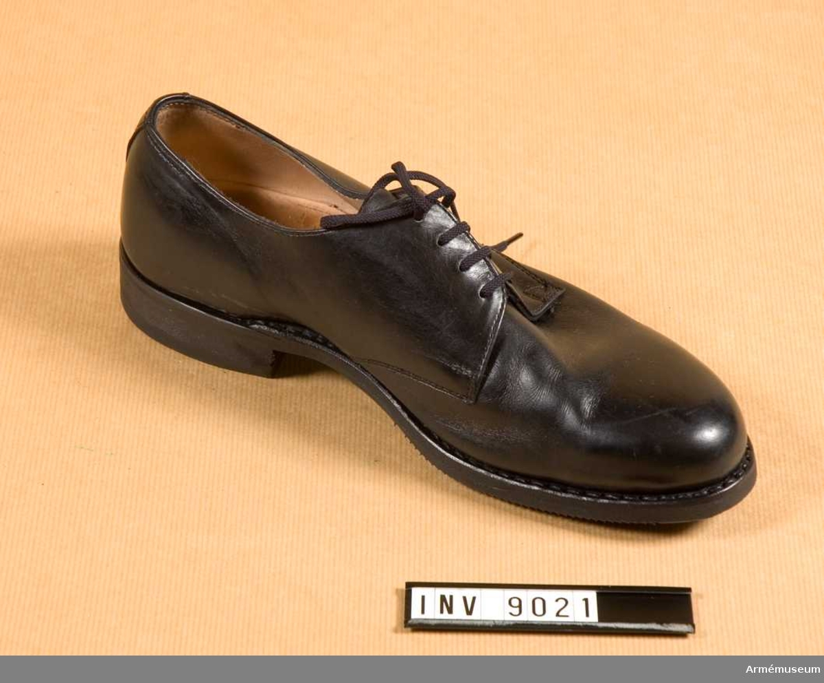 Sko för vänster fot av svart läder med låg klack och rund tå. Får endast bäras till långbyxor.
Svart gummisula räfflade som i hålfoten är märkt TRETORN 1977 36 (storlek). Klacken är märkt TRETORN H 17.