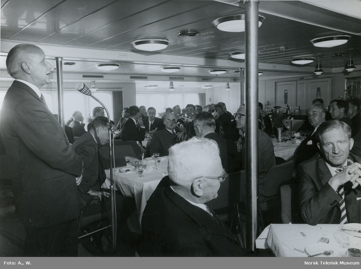 Mann holder tale under prøvetur med passasjerskipet M/S Nordnorge, B/N 550 i Oslofjorden 5. juni 1964. Skipet ble levert av Akers Mek. Verksted til Ofotens Dampskipsselskap under denne prøveturen.