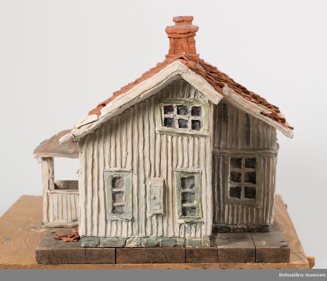Skulpturens titel: "Övergivet hus i Bohuslän"
Hus skulpterat i lera, bemålat med oxidglasyr och bränt i ugn.
Förebilden är ett bohuslänskt dubbelhus  i förfallet skick. genom åren tillbyggt och ändrat.
Detaljerna är noga redovisade.