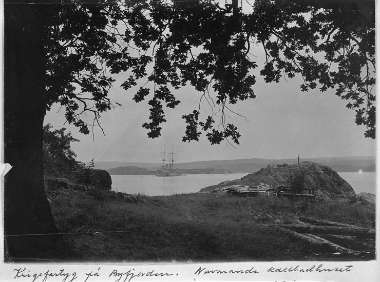 Text på kort: "Krigsfartyg på Byfjorden. Nuvarande kallbadhuset å Gustafsberg ligger på klippan med trävirket".