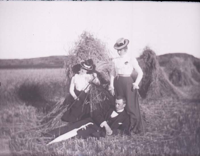 Enligt text som medföljde bilden: "Anne Lyzell, Aågot Stub, Hugo Hallgren vid en sädesskyl. Taget af Valter Lycke Fiskebäck 6/8 1899".