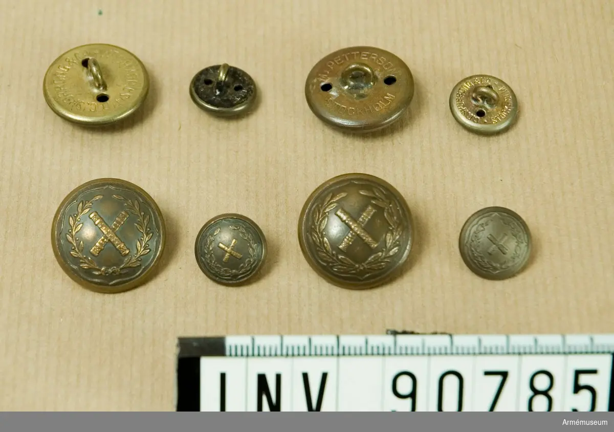 Låda innehållande en stor mängd bronserade knappar. Även en liten påse med knappar m/1904.
