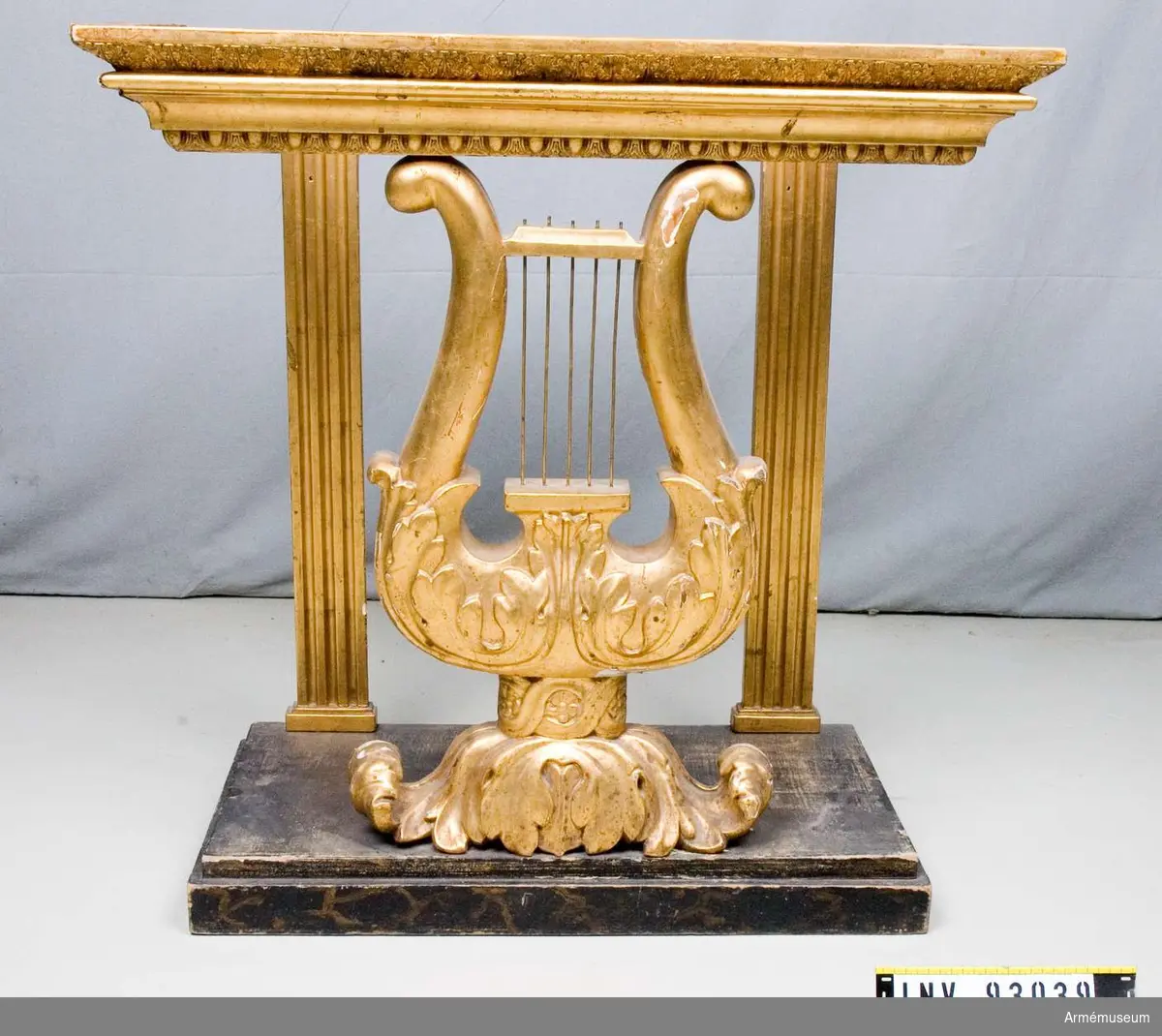 Förgyllt bord i form av ett musikinstrument med bordskiva av marmor. Ska stå under en spegel.