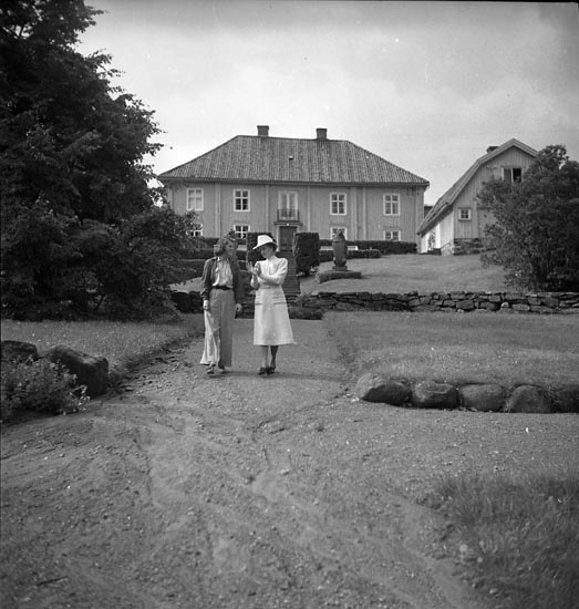 Två kvinnor promenerar i trädgården på Morlanda Säteri