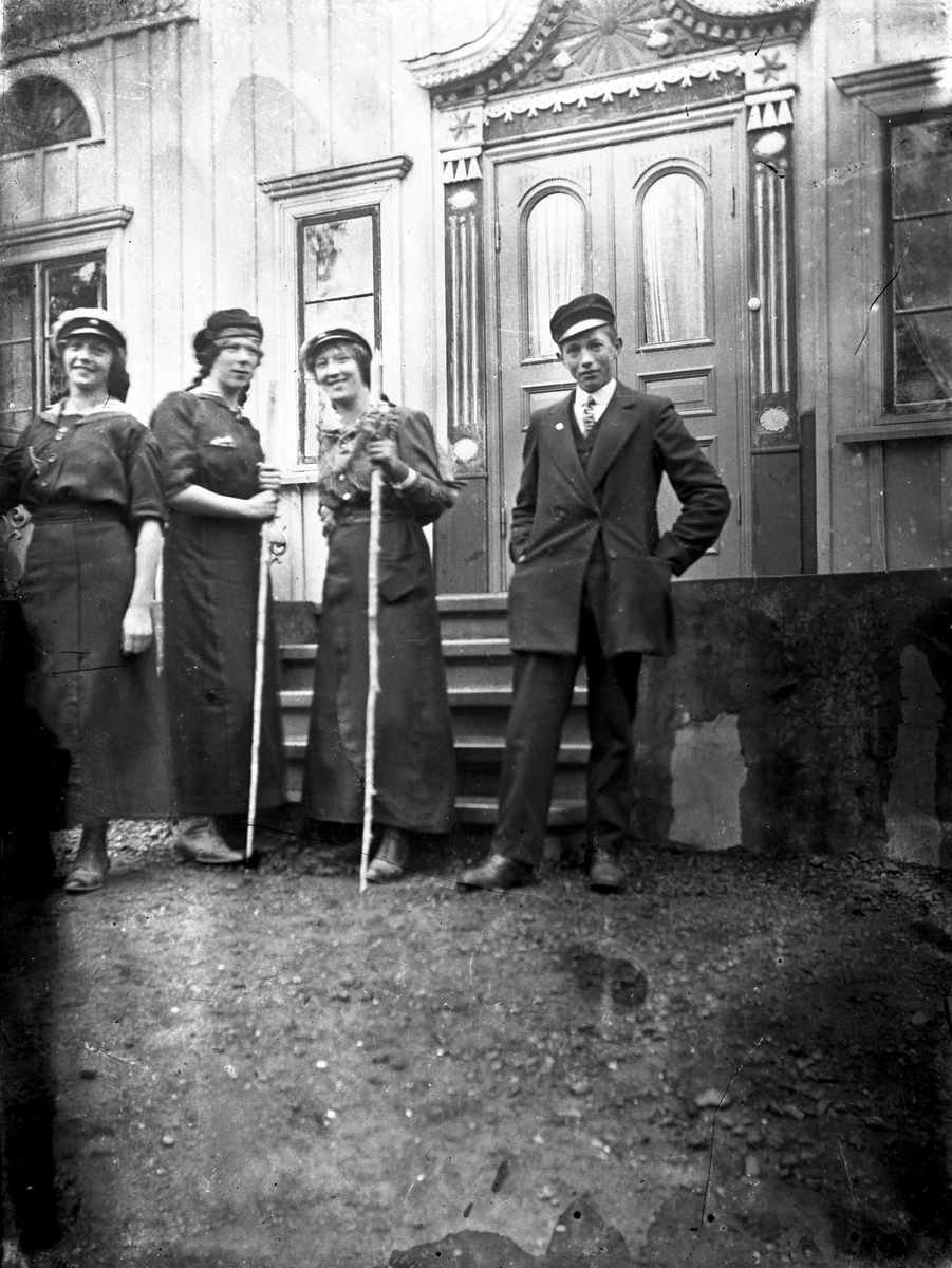 Fyra ungdomar med examensmössor på huvudet står vid ett hus i Forserum. Det har en vackert utsirad ingång.