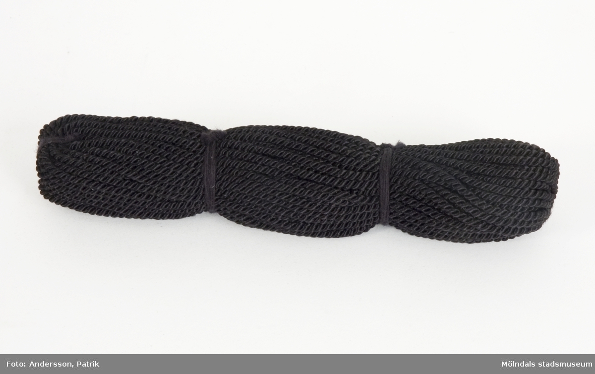 Silkesnöre, tvinnat, svart i garndocka. Snöret användes för bokbindning på Papyrus, på Kuverteringen. 