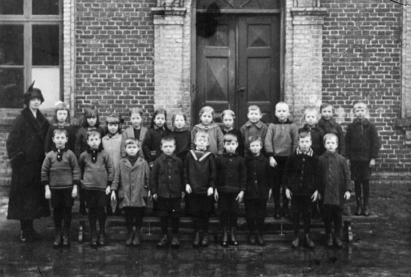 Lärarinnan Agda Karlsson med elever som står uppställda framför Grevedämmet port mellan 1925 och 1955.