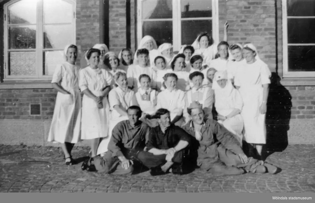"Karantänsförläggning" på Kvarnbyskolan för överlevande från koncentrationsläger i Tyskland och Polen 1945.  
Skolan fungerade under denna sommar som beredsskapssjukhus.

Sjuksköterskor och personal står uppställda, några sitter, utanför byggnaden.