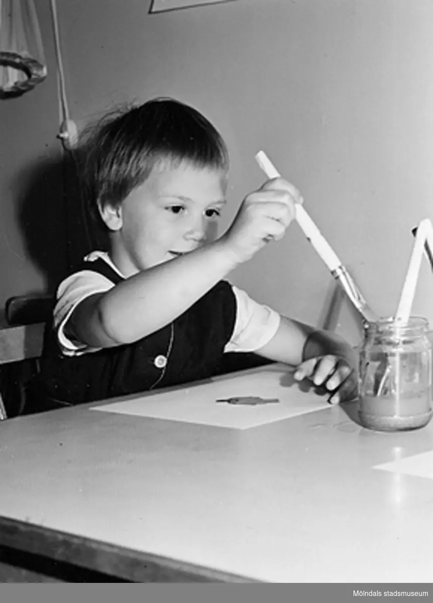 Ett barn som målar med penslar vid Holtermanska daghemmet 1953.