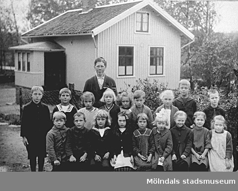 Ingrid Larssons skolklass utanför skolan i Livered, Kållered, 1920-talet. Småskollärarinna Hulda Holmén.