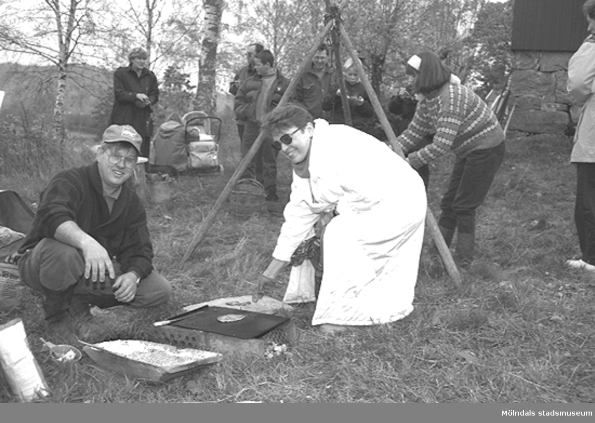 Familjesöndag vid Börjesgården, 1994-05-15. Museitekniker Alf Garthman sitter på huk och grillar. Museichef Mari-Louise Olsson kokar mat över öppen eld.