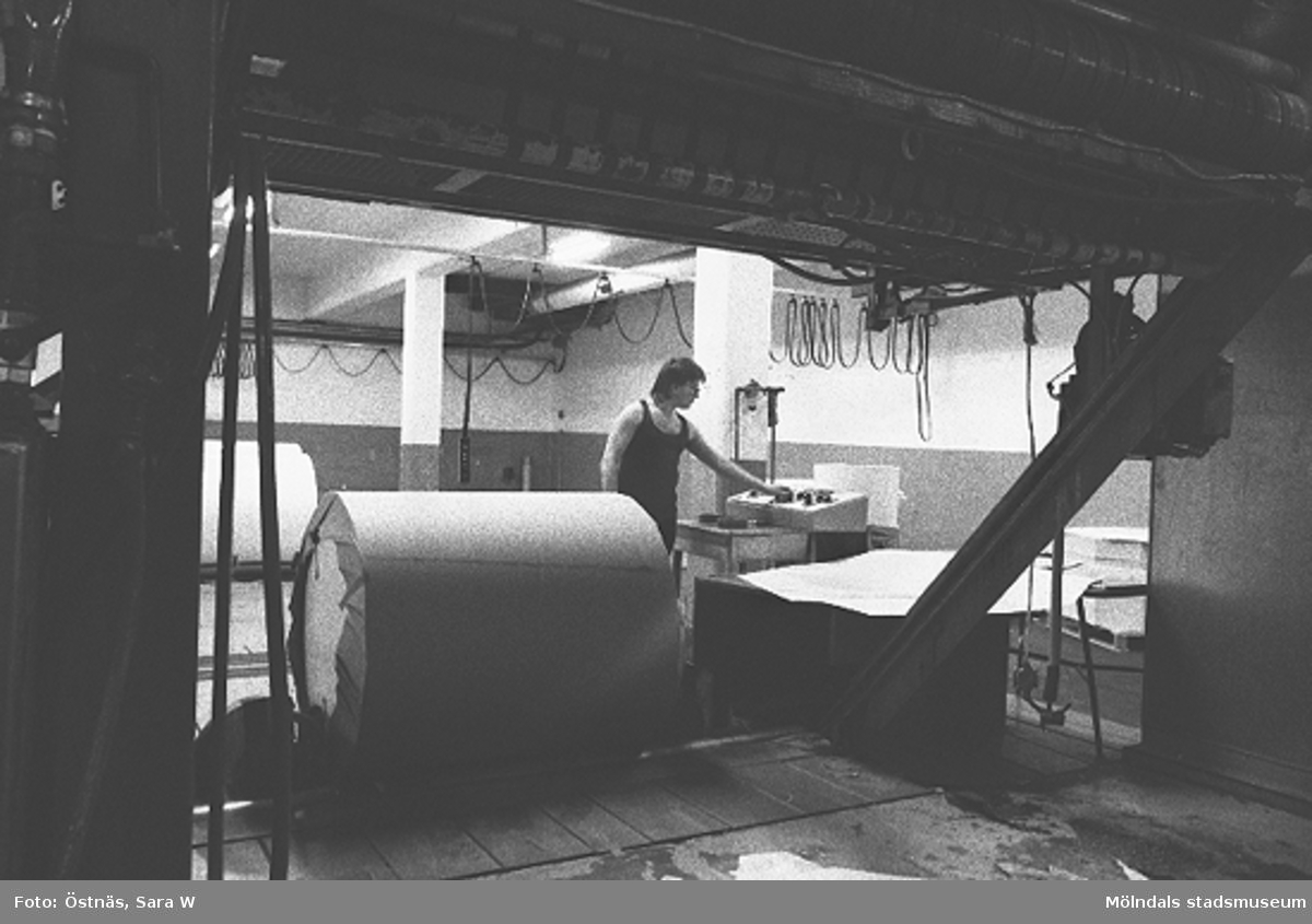 En man i arbete med en pappersbal, 1980-tal.
Bilden ingår i serie från produktion och interiör på pappersindustrin Papyrus.