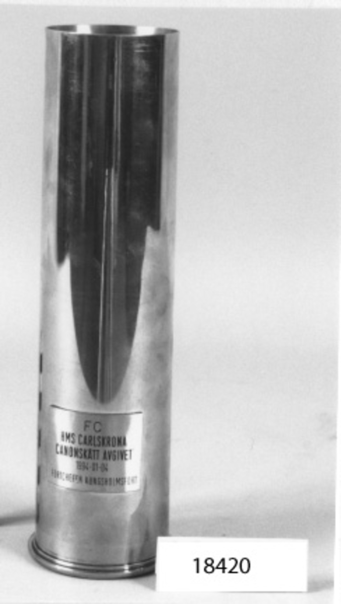 Ammunitionshylsa av mässing, cylinderformad, avskuren på mitten och förändrad till minnesföremål.