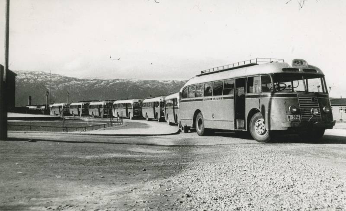 7 av Ofotens Bilruters busser passerer torvet i Narvik.  Fontenen er tildekker for vinteren.