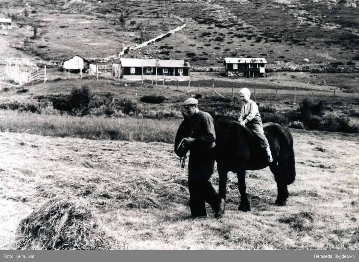 Hensrudvollen på Løkenstølane i Hemsedal i 1953. Torleiv Hensrud leier hesten medan Yngvar Hjelm sit på hesteryggen.