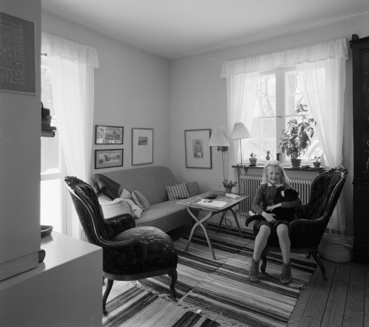villa Ahlgren
Interiör, litet förmak med läsande flicka vid sittgrupp med soffa och emmastolar