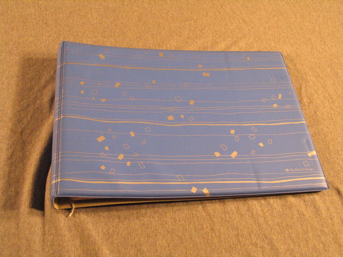Album med blått plastomslag, rektangulært og 15 ubrukte ark. 