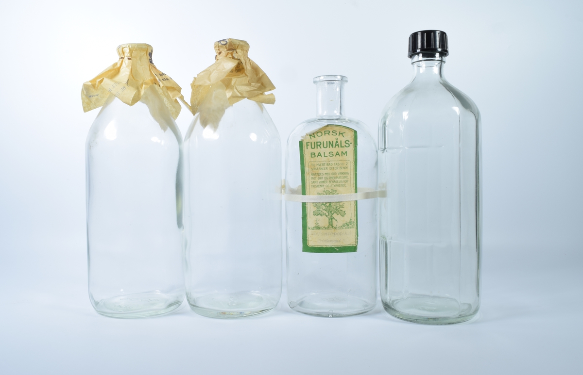 Fire flasker i klart glass.

a-b: Glassflasker med papirkork.

c: Glassflaske uten kork. Gulnet etikett med grønn ramme og motiv av et furtre.

d: Mangekantet glassflaske med sort plastkork.