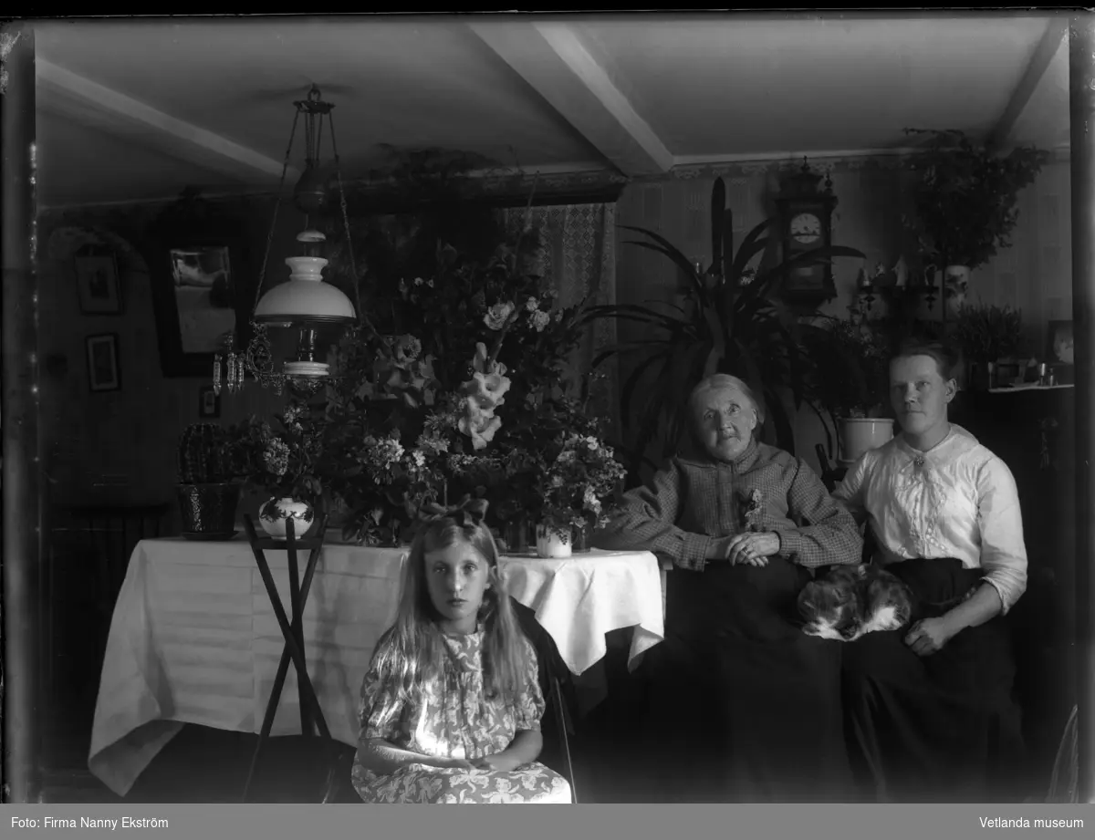 En flicka och två kvinnor vid ett bord med blommor.