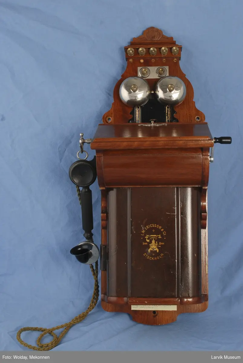 Form: Telefon kasse med lokk til å åpne. Telefon røret henger på venstre side. Sveiv på høyre siden.  

Manuell
