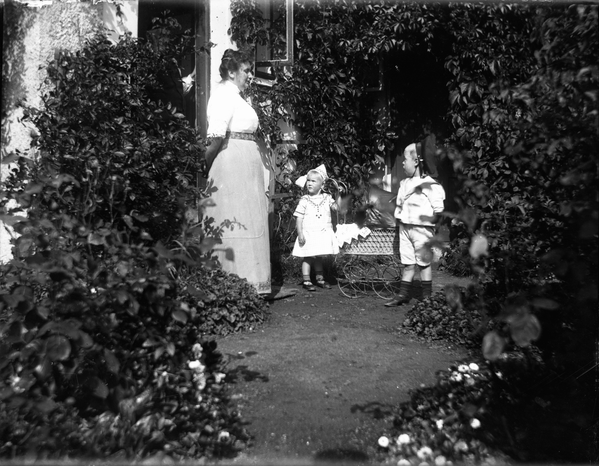 Lyng Olsens hus med hage ved Biørnsborgparken, Kragerø. Karen Lyng Olsen står med sine barn Helen og Burton Lyng Olsen.
