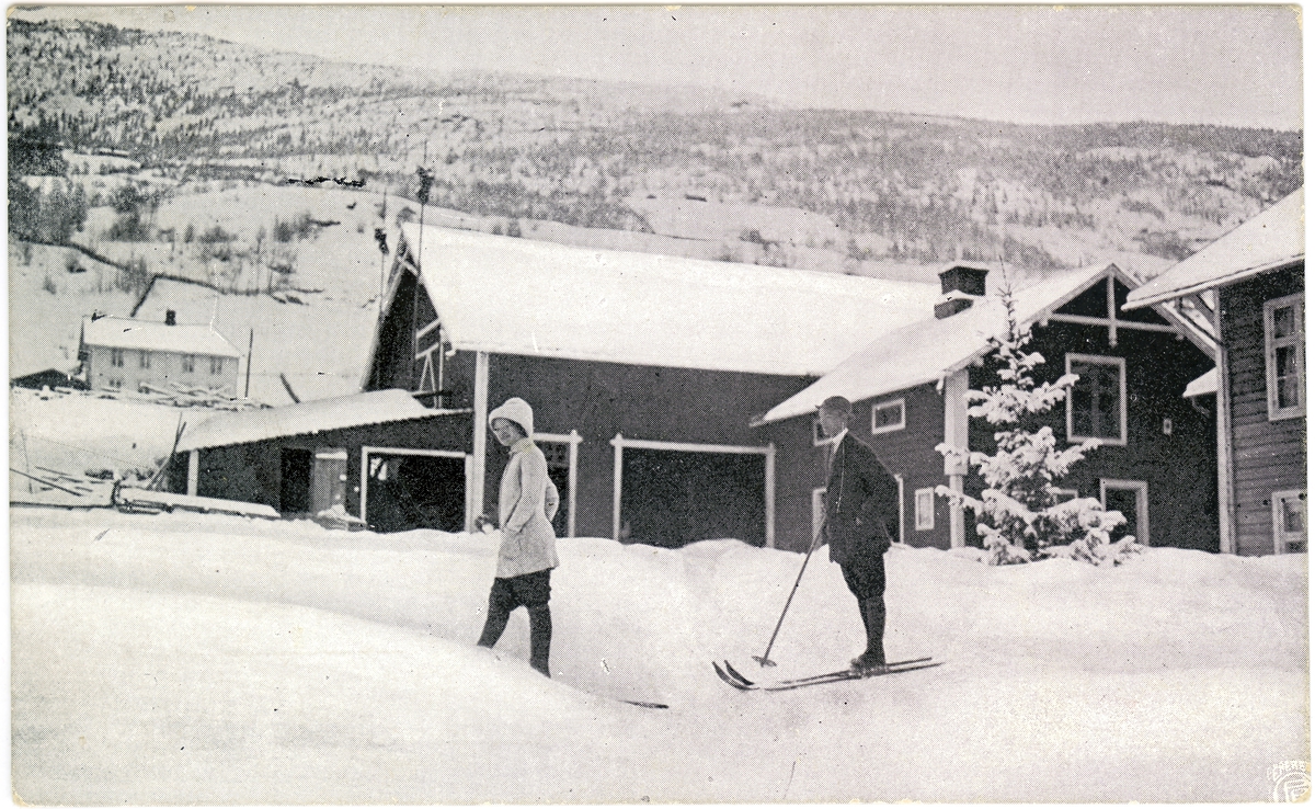 Skiløpere foran gårdsbebyggelse