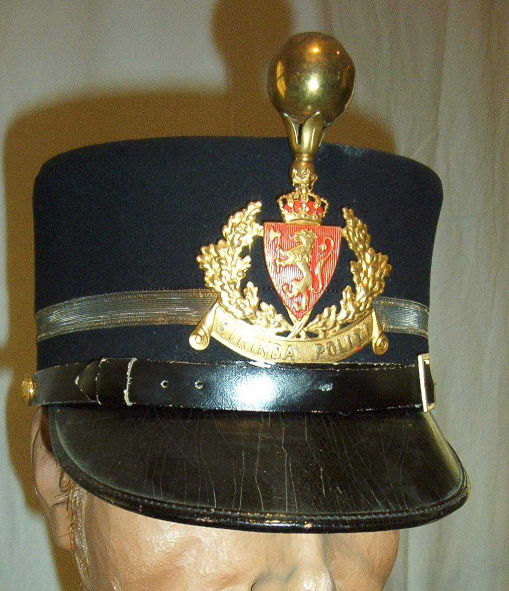 Uniformslue modell 1907. Det står Strinda Politi på skiltet.