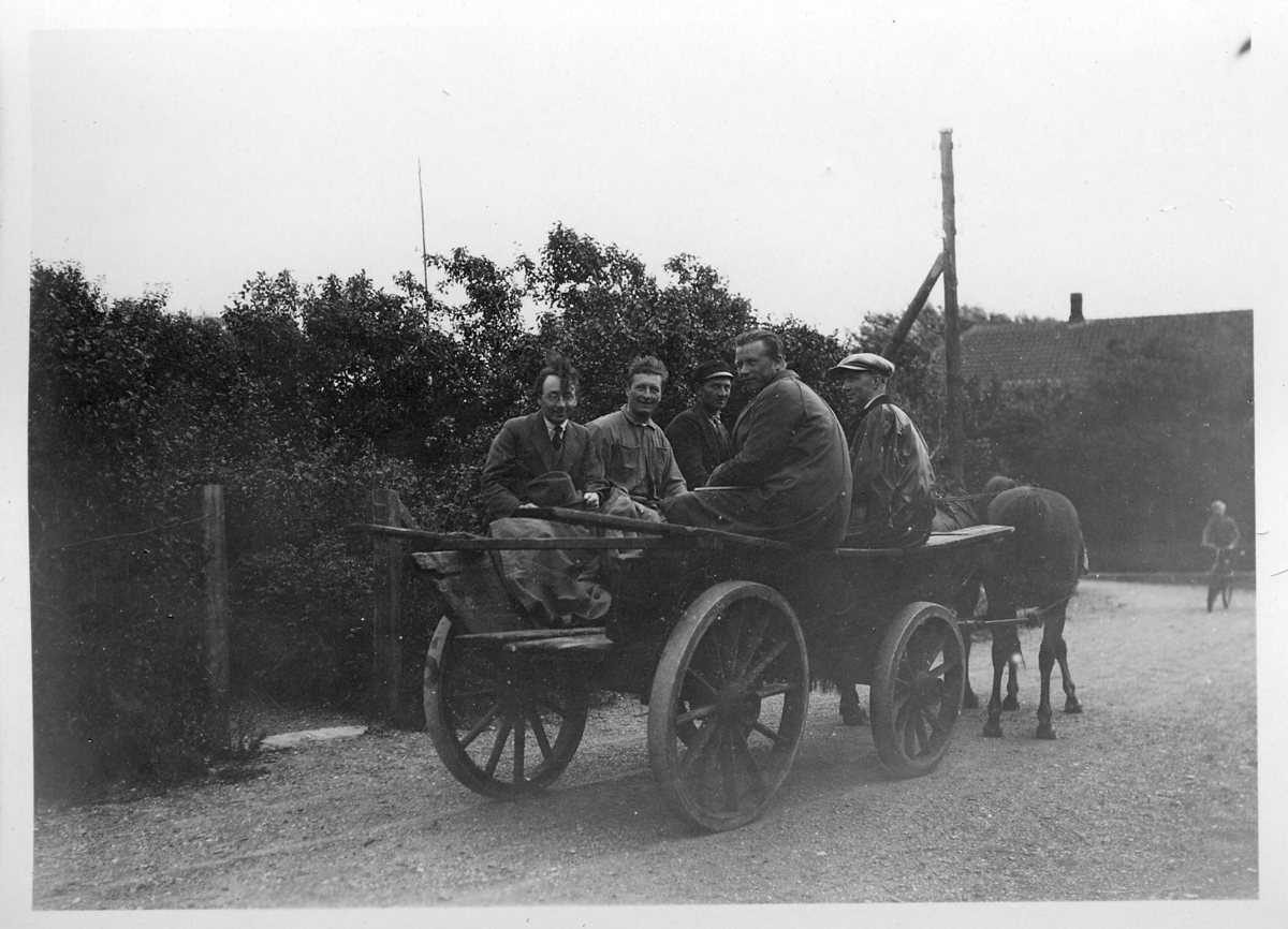 'Akka-expeditionen sommaren 1930: ::  :: På väg från fyren. 5 st män sitter i en vagn dragen av 2 st hästar. I bakgrunden 1 person på cykel. Trädgård i bakgrunden. ::  :: Ingår i serie med fotonr. 2033-2087.'