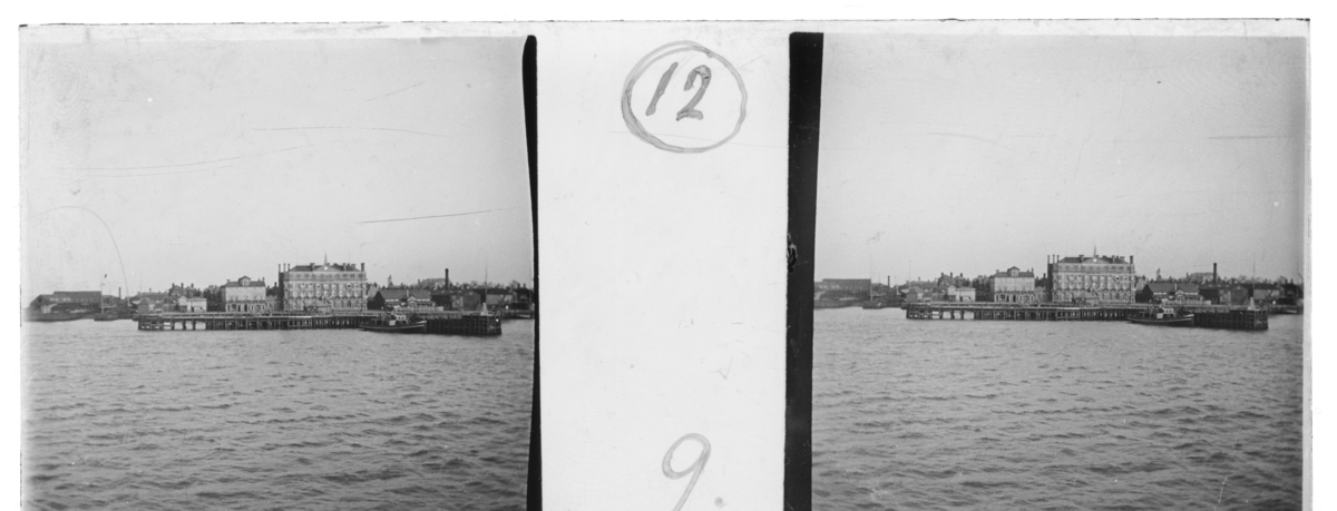 'Vy in mot Harwich med hamn, båt och byggnader. :: Enligt text till fotot: ''North Sea voyage. Harwich, from streamer.'' (Nordsjöseglats. Harwich sett från ångbåten.) ::  :: Ingår i serie med fotonr. 5245:1-20, se även hela serien med fotonr. 5237-5267.'