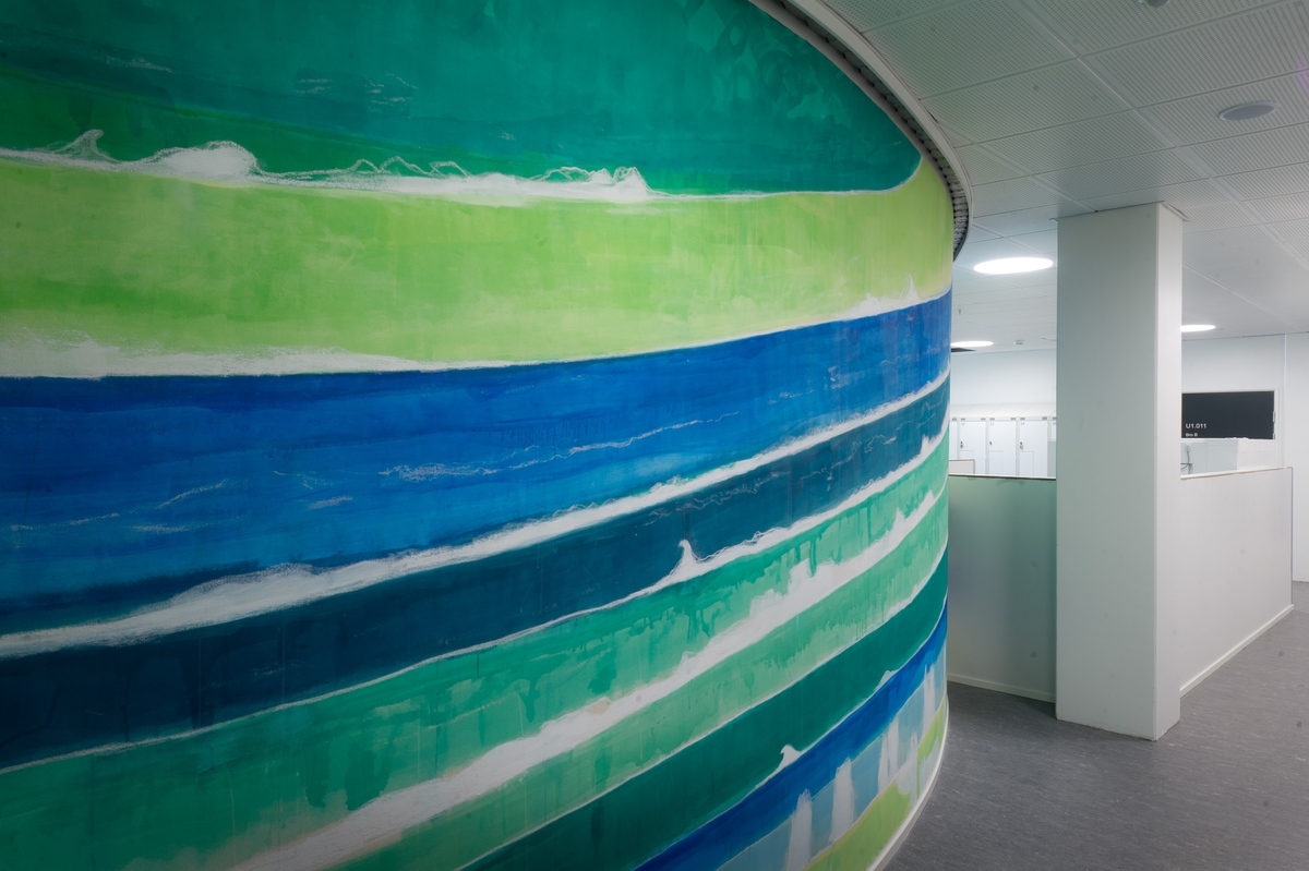 Maleriet viser abstraherte bølgeformer i grønt og blått som et heldekkende sceneteppe til bølgeteateret i simulatoren innenfor.